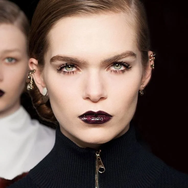 Deux femmes avec maquillage audacieux, ambiance sombre.